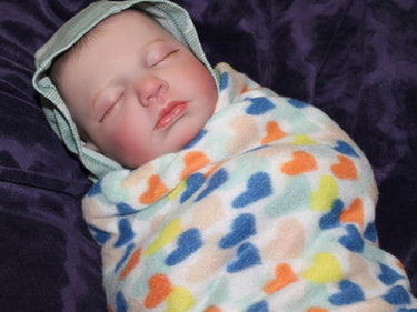 A baby resting on a bed, adorned with a charming hat, surrounded by cozy blankets.